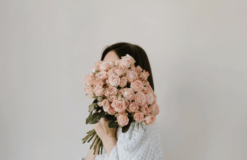 a female with flowers on hand covering her face